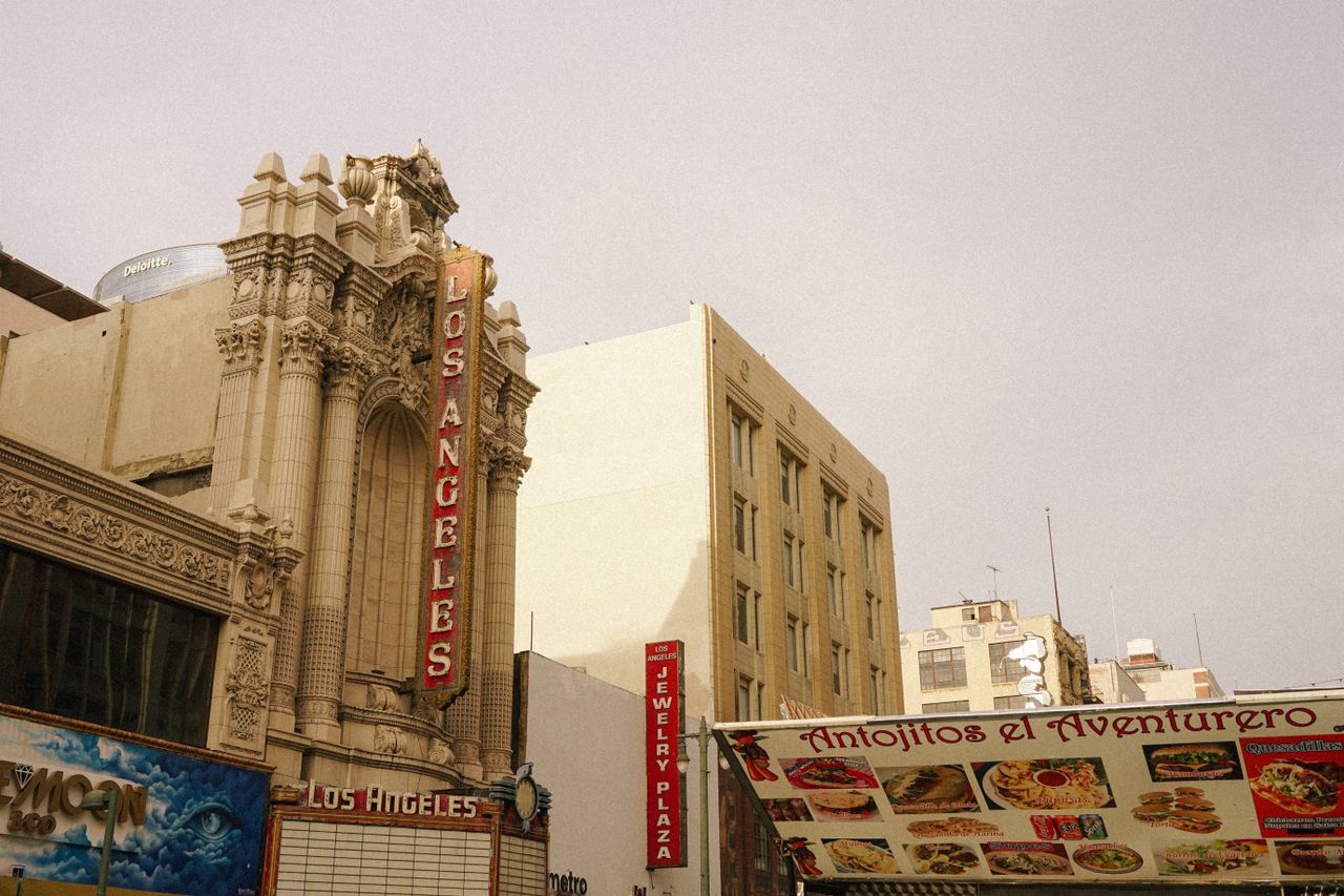 A vintage view of Los Angeles theater with a bustling street market in the foreground.